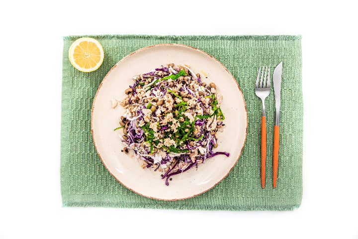Plate of salad with a fork and knife on a green placemat